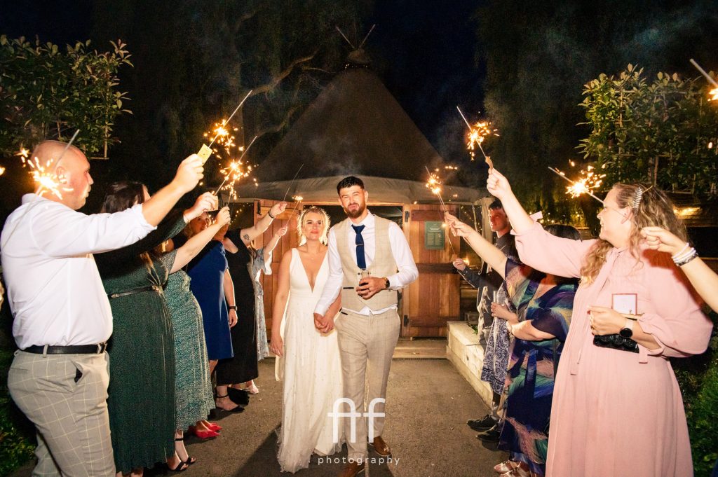 Newly-wed couple walking through a sparkler exit at Woodlands at Hothorpe in Leicestershire
