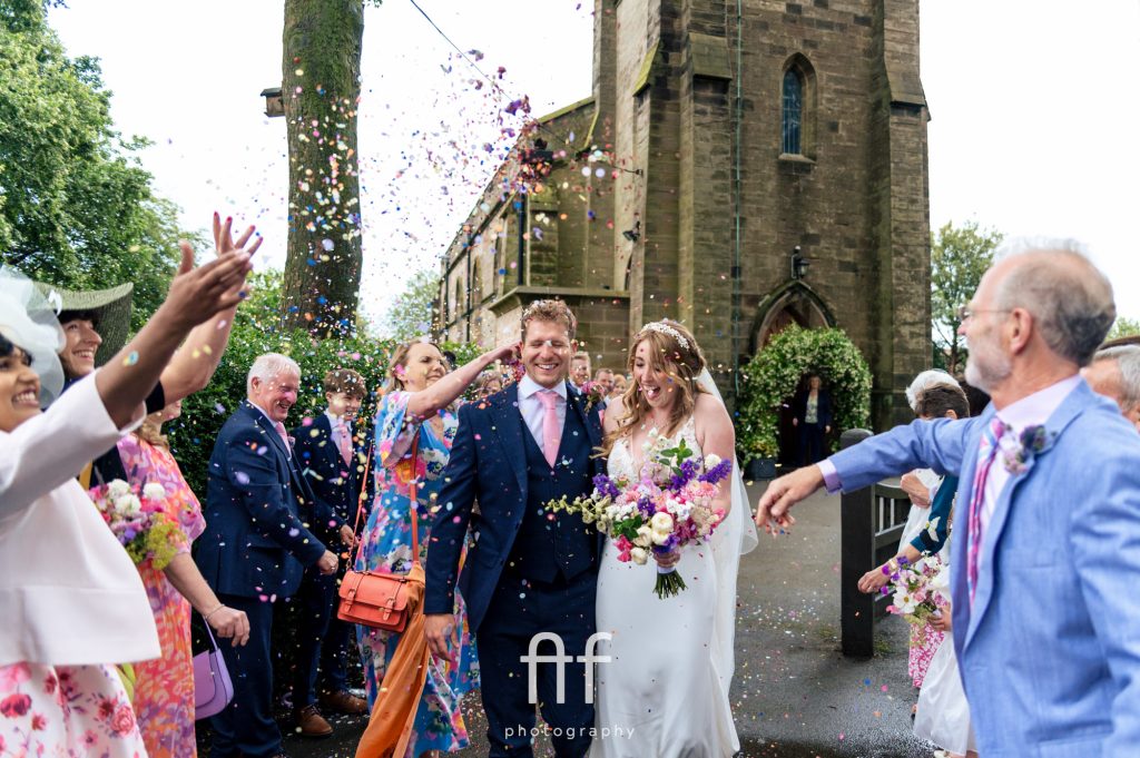 Couple having confetti thrown at them and the brides dad at the front trying to get more confetti on them